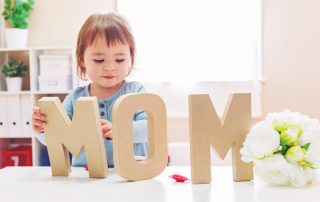 small child with MOM letter cutouts